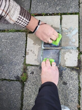 Zwei Stolpersteine die mit Schwämmen gereinigt werden