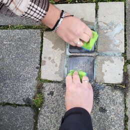 Zwei Stolpersteine die mit Schwämmen gereinigt werden